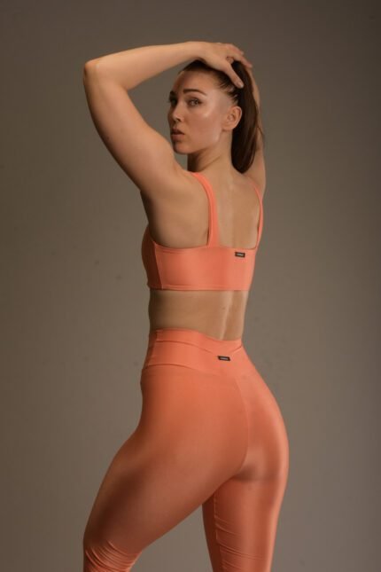 Naisten oranssi urheilutoppi, jossa kiiltävä pinta ja keskitasoinen kompressio.