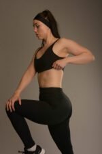 Naisten musta urheilutoppi ohuilla olkaimilla ja ribbikankaisilla yksityiskohdilla